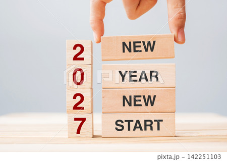 hand holding wooden block with text 2027 NEW YEAR NEW START on table background. Resolution, strategy, solution, business and holiday concepts 142251103