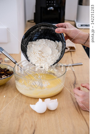 Cooking dough. Pouring flour. Female confectioner hand adding dry baking ingredient to bowl preparing meal tasty recipe at home kitchen. 142251283