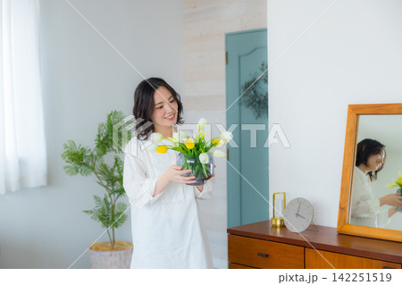 リビングで花瓶を持つる若い女性 リビングで花瓶を持つる若い女性 142251519