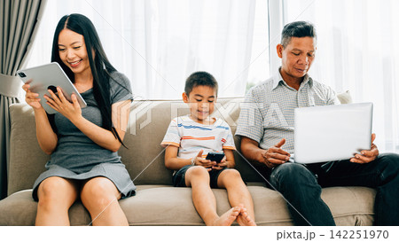 An Asian family engrossed in devices at home neglects bonding time An Asian family engrossed in devices at home neglects bonding time 142251970