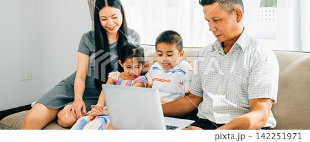 A cheerful family seated on a cozy sofa sharing a laptop parents and kids engaged in online browsing 142251971