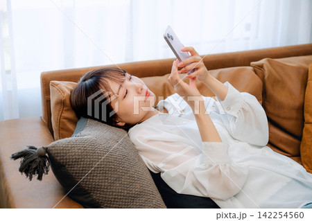 屋内でスマホを見る若い女性 屋内でスマホを見る若い女性 142254560