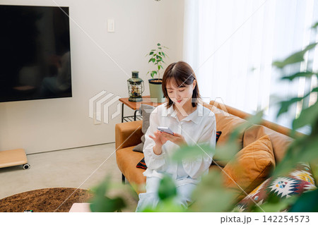 自宅リビングでくつろぐ20代女性 自宅リビングでくつろぐ20代女性 142254573