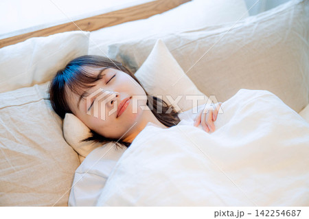 寝室のベッドで眠る若い女性 寝室のベッドで眠る若い女性 142254687