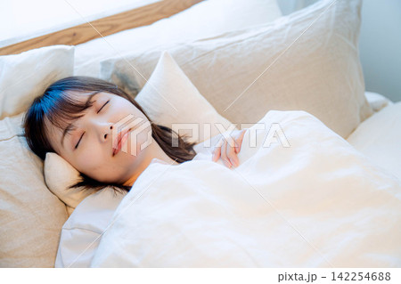 ベッドで睡眠をとる若い女性 ベッドで睡眠をとる若い女性 142254688