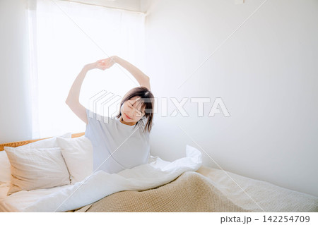 ベッドの上でストレッチをする女性 142254709