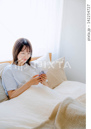 ベッドでスマホを使う若い女性 ベッドでスマホを使う若い女性 142254727