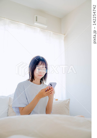 寝室のベッドでスマホを使う女性 寝室のベッドでスマホを使う女性 142254742