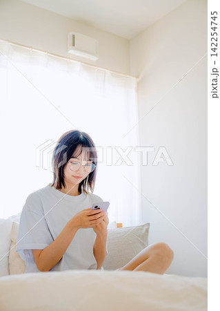 ベッドの上でスマホを使う女性 ベッドの上でスマホを使う女性 142254745
