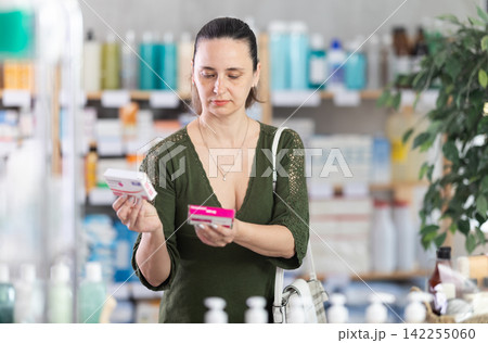 Middle-aged woman customer choosing paracetamol in drugstore Middle-aged woman customer choosing paracetamol in drugstore 142255060