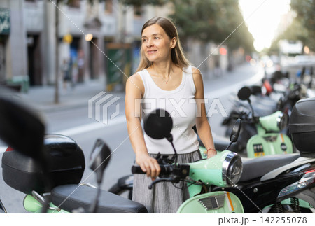 Woman rents moped, starts journey at parking lot Woman rents moped, starts journey at parking lot 142255078