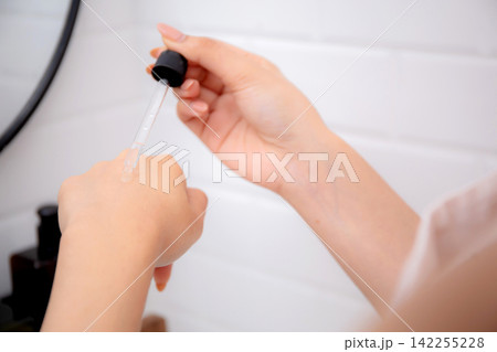Closeup hands young asian woman applying serum for rejuvenation on hands looking mirror. Closeup hands young asian woman applying serum for rejuvenation on hands looking mirror. 142255228