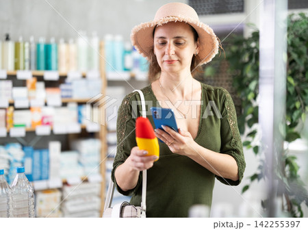 Woman in pharmacy scans QR code on mosquito repellent 142255397