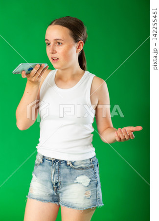 Teenage girl records an audio message on smartphone. Chroma key compositing Teenage girl records an audio message on smartphone. Chroma key compositing 142255481