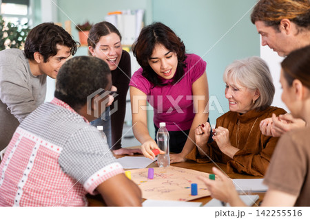 Group of focused people playing board game around a table Group of focused people playing board game around a table 142255516