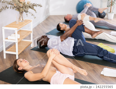 Young woman doing yoga in group in studio Young woman doing yoga in group in studio 142255565