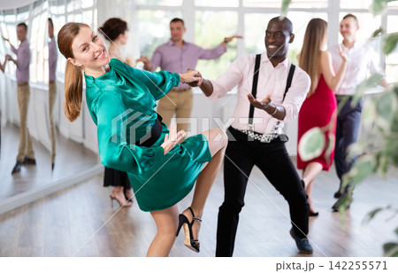 Group of men and women in festive clothes dancing foxtrot in dance studio Group of men and women in festive clothes dancing foxtrot in dance studio 142255571