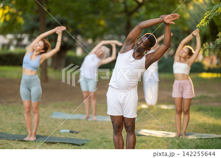 African man standing in Nitambasana during yoga practice in park 142255644