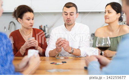 Joyful middle-aged men and women playing poker at home 142255677