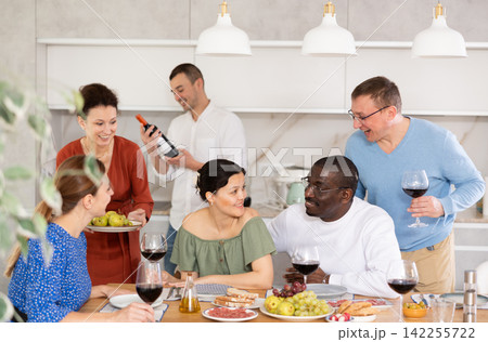 Happy middle-aged friends drinking wine and having friendly conversation around the table Happy middle-aged friends drinking wine and having friendly conversation around the table 142255722