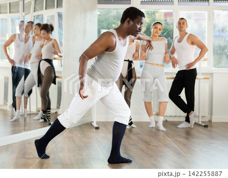 African american man shows ballet positions to a group of students in ballet studio African american man shows ballet positions to a group of students in ballet studio 142255887