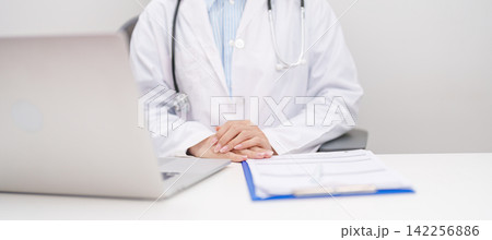Professional doctor wearing lab coat and stethoscope using laptop computer and taking report notes on notebook at desk in hospital clinic office, medical technology and healthcare concept Professional doctor wearing lab coat and stethoscope using laptop computer and taking report notes on notebook at desk in hospital clinic office, medical technology and healthcare concept 142256886