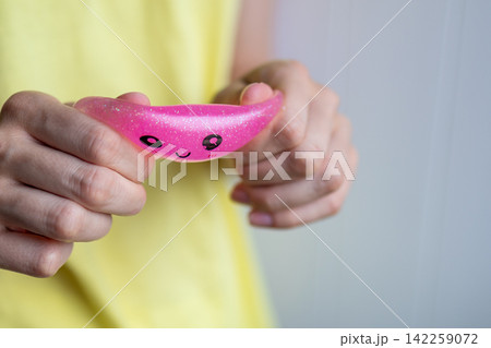 Hands stretch a pink squishy toy showing its flexible texture during sensory play. Concept of tactile exploration, stress relief, flexibility and sensory activity. Hands stretch a pink squishy toy showing its flexible texture during sensory play. Concept of tactile exploration, stress relief, flexibility and sensory activity. 142259072