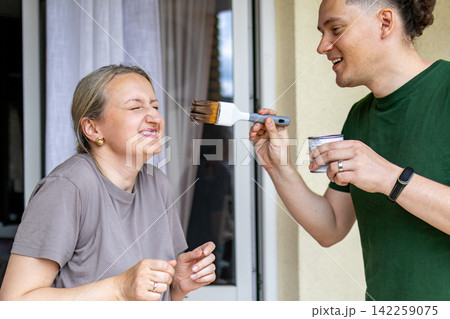 Couple laughs while taking a playful break during a DIY furniture project on a balcony workspace. Concept of partnership, positive teamwork, modern relationship and home improvement. Couple laughs while taking a playful break during a DIY furniture project on a balcony workspace. Concept of partnership, positive teamwork, modern relationship and home improvement. 142259075
