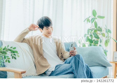 リビングでスマホを見る男性 142261772