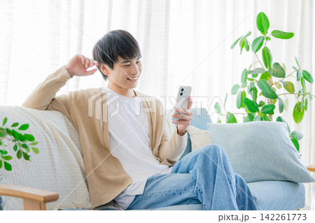 リビングでスマホを見る男性 142261773