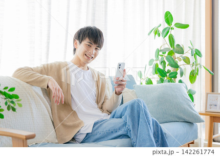 リビングでスマホを見る男性 142261774
