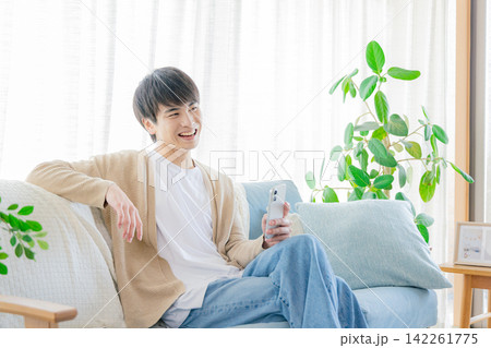 リビングでスマホを見る男性 142261775
