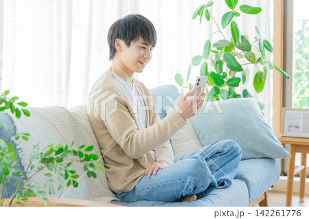 リビングでスマホを見る男性 リビングでスマホを見る男性 142261776