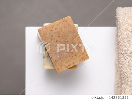 Beige soap basr on white near beige towel. Unbranded packaging Beige soap basr on white near beige towel. Unbranded packaging 142261831