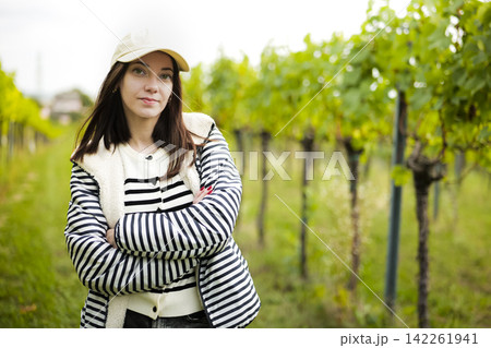 Young woman posing in a vineyard, illustrating the authentic Austrian countryside during the grape ripening season. Young woman posing in a vineyard, illustrating the authentic Austrian countryside during the grape ripening season. 142261941