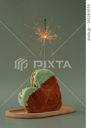 Festive holiday candle sparkler birthday anniversary celebration Heart shaped pistachio croissant on green background with copy space. Puff pastry trendy sweet dessert bakery. Creamy dough experiment Festive holiday candle sparkler birthday anniversary celebration Heart shaped pistachio croissant on green background with copy space. Puff pastry trendy sweet dessert bakery. Creamy dough experiment 142263014