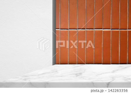 White marble table top display and orange brown ceramic tile wall background for product presentation. White marble table top display and orange brown ceramic tile wall background for product presentation. 142263356