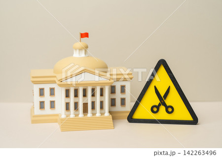 Government building and budget cut symbol. National budget sequestration. Reduction of public employees and personnel to save funds. Fiscal austerity reshapes government operations. Government building and budget cut symbol. National budget sequestration. Reduction of public employees and personnel to save funds. Fiscal austerity reshapes government operations. 142263496