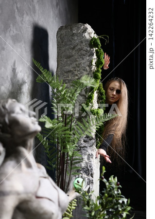 Mystical female figure in ruined mossy landscape with dreamy lighting Mystical female figure in ruined mossy landscape with dreamy lighting 142264232