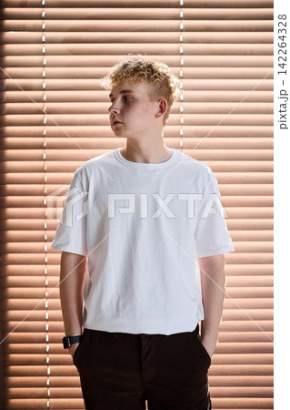 Teen gazes outward. Young person observes window sunlight Teen gazes outward. Young person observes window sunlight 142264328