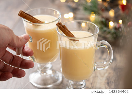 Hand picking up a glass of eggnog from a Christmas table 142264402