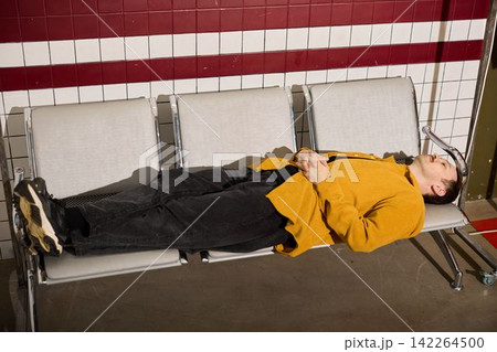 Individual dressed in streetwear taking break in subway station Individual dressed in streetwear taking break in subway station 142264500