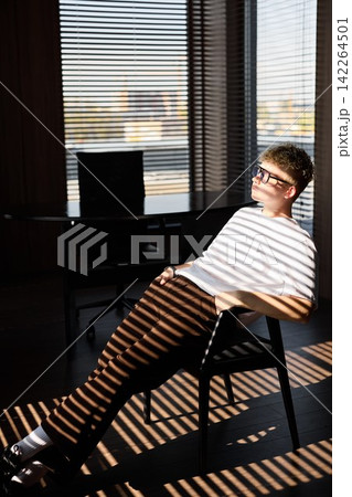 Young male with light stripe pattern relaxing inside modern home Young male with light stripe pattern relaxing inside modern home 142264501