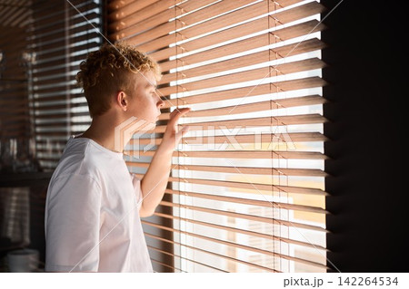 Teenage boy with relaxed stance watches local street scene in daylight 142264534