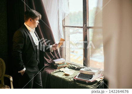 Man in formal attire evaluates images and correspondences in office Man in formal attire evaluates images and correspondences in office 142264676