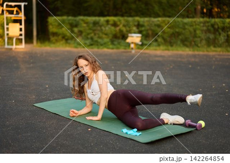 Trainer demonstrating sideline glute activation exercise outdoors Trainer demonstrating sideline glute activation exercise outdoors 142264854