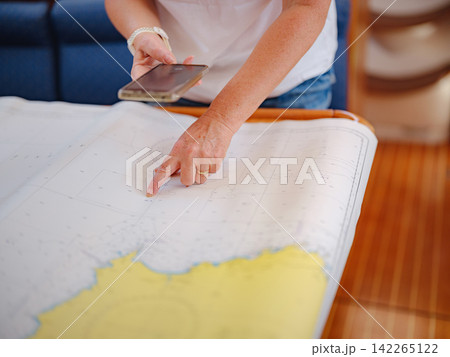 Woman Sailor Studying Navigation Map Inside Yacht Cabin Interior 142265122