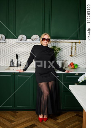 Fashionable woman poses confidently amidst modern kitchen decor elements Fashionable woman poses confidently amidst modern kitchen decor elements 142265190