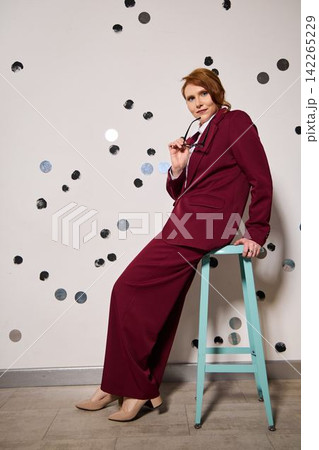 Caucasian podcast host in burgundy dress with microphone Caucasian podcast host in burgundy dress with microphone 142265229