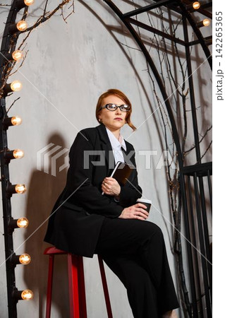 Executive woman analyzes notes in dramatic studio environment Executive woman analyzes notes in dramatic studio environment 142265365
